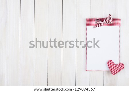 Notebook and heart on wooden background
