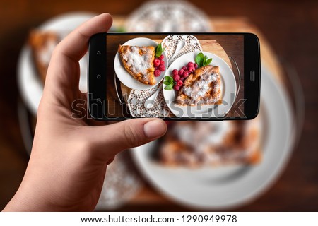 Men hands  takes photography of food on table with phone. Apple pie with raspberries and mint. Smartphone photo for post on social networks.