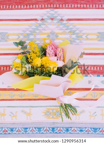 Spring bouquet with mimosa, roses and greenery on a bright background. Close-up, vertical