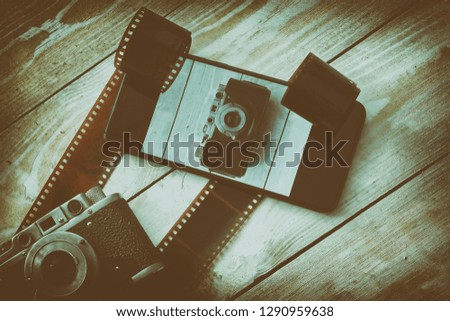 vintage camera and modern black smartphone on wooden light background, the concept of the development of photographic equipment and electronics, toned