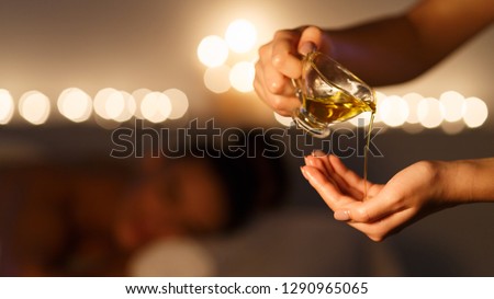 Masseur pouring massage oil, woman lying on background at spa center Royalty-Free Stock Photo #1290965065