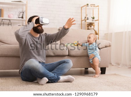 Interested baby watching like his father using virtual reality headset, copy space