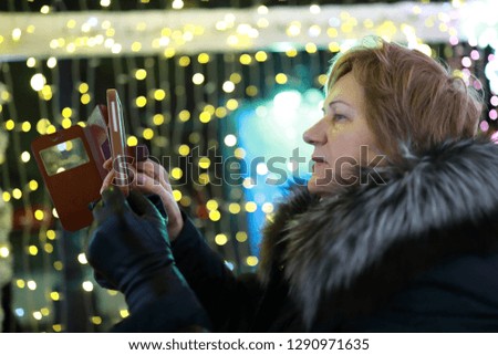 Woman taking pictures on smartphone in city at night