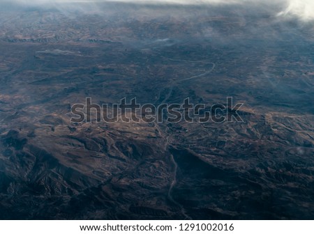 A view through plane window with mountains and clouds