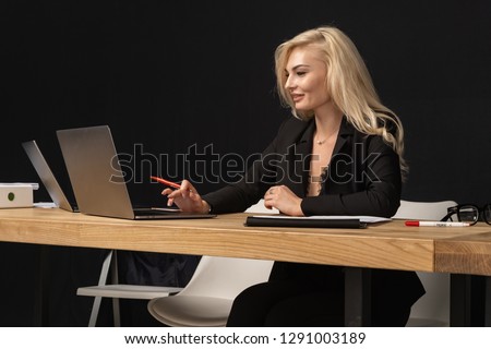Beautiful blonde woman intelligent managing director is keyboarding on laptop computer, while is sitting in modern office interior.