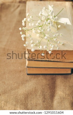 Vintage spring background with white flowers, a yellowed old books on the burlap. closeup.