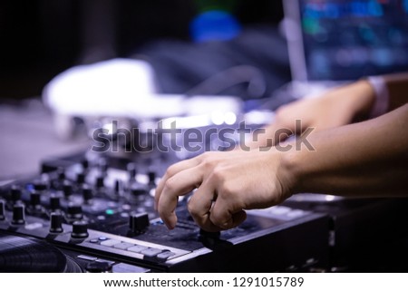 Hip hop party dj scratches vinyl record with music on stage in night club. Hands of disc jockey mixing musical tracks with sound mixer and retro turntables. Disk jokey scrathing records on party
