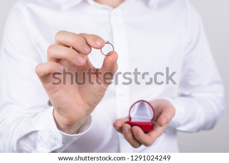 Closeup photo cropped picture of happy cheerful excited glad positive optimistic guy holding small little ring in hand with fingers isolated grey background