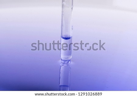 Pipette immerses with liquid in water with reflection