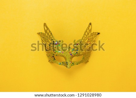 Table top view aerial image of beautiful colorful carnival season or photo booth prop Mardi Gras background.Flat lay object gold mask on modern yellow wallpaper.Free space for creative design mock