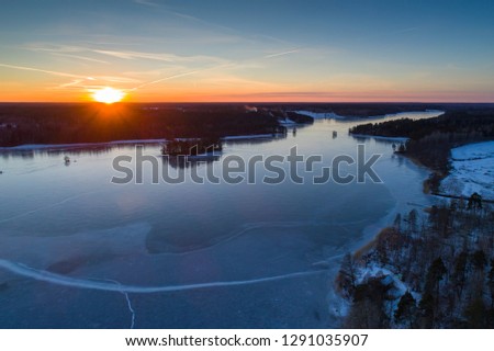 Beautiful nature and landscape at cold winter evening in Sweden Scandinavia Europe. Nice sunset and frozen ice lake. Shot with drone from above in sky. Calm, peaceful and happy outdoor image.