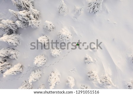 Sunny winter landscape with man on snowshoes in the mountains, aerial view.