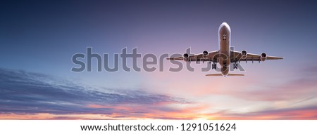 Commercial airplane jetliner flying above dramatic clouds in beautiful sunset light. Travel concept. Royalty-Free Stock Photo #1291051624
