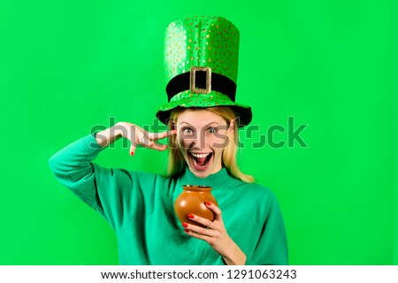 Smiling blonde girl in Leprechaun costume holds pot with gold. Green hat. Leprechaun. Pot with gold. Green leprechaun. Hat with clover. Saint Patrick's Day. Irish Traditions. Saint Patrick.