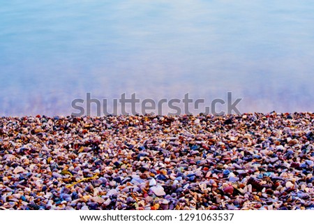 Colorful sea pebbles on the shore and clear water 
