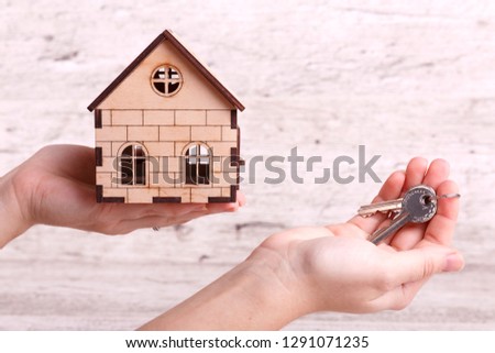 House key in hand. Hand holding home in palm and key on finger