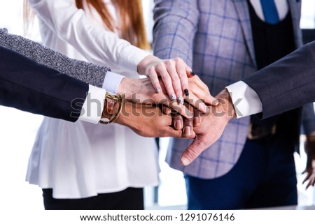 Focused on the work of business people from different countries put their hands on each other showing cohesive work close-up Royalty-Free Stock Photo #1291076146