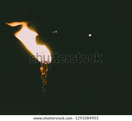 The picture shows a candle stuck on a beach during a warm summer party evening.