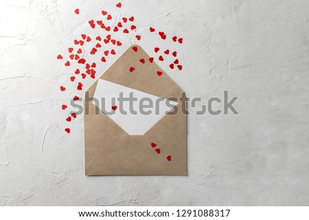 Valentines day minimal concept, hanmade gift - craft envelope with blank nore, pink and white paper hearts on gray background