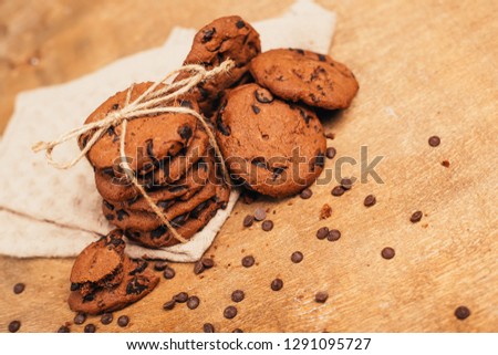 image shows a stack of american chocolate chip cookies on rustic wooden plank