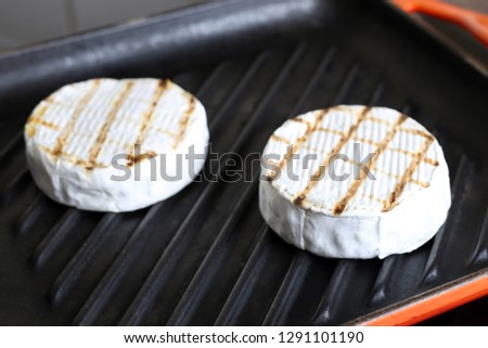 Tasty chequered camembert cheese frying on cast iron grill pan. Fresh grillde brie cheese