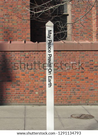 Sign on a sidewalk street in the city that reads - May peace prevail in earth