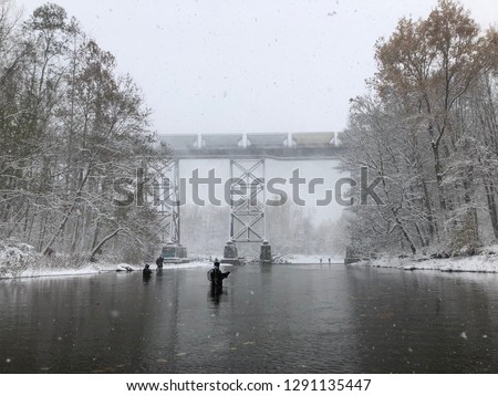 Steelhead fisherman in Snowy River Stream in the snow next to a train bridge Erie Pa