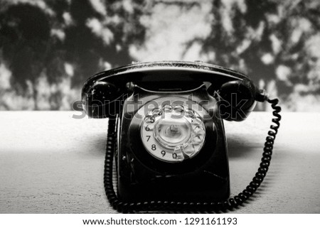 Retro rotary telephone on old table, black and white photo