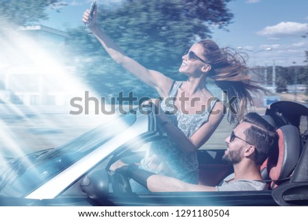charming young couple taking selfie in car