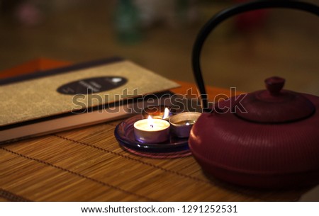 a nice picture of kettle with tea, candles and book