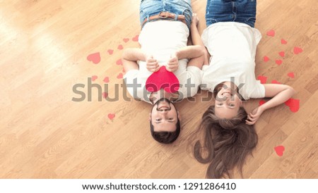 Funny couple in love lying on the wood floor and laugh.