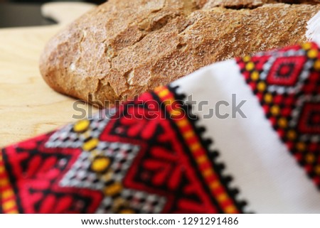 Gold rustic crusty loave of bread on the wooden board on black background. Top view, flat lay. Layout with free copy (text) space.