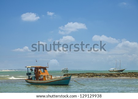 fishing boat anchored close to a reef. Royalty-Free Stock Photo #129129938