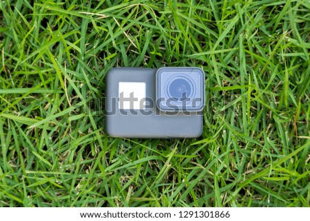 black action camera lies in the green grass.