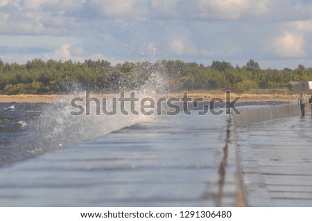 The pier with water splashes, clouds in the sky on a sunny day