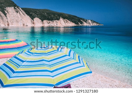 Tranquil beach scene. Picturesque landscape of mediterranean island with colorful umbrellas. Summer vacation holiday concept