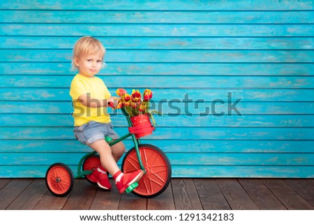 Funny child riding bike. Happy kid having fun at home. Spring family holiday concept. Mother's day