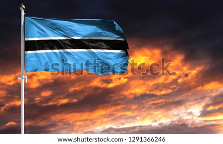flag of Botswana on flagpole fluttering in the wind against a colorful sunset sky