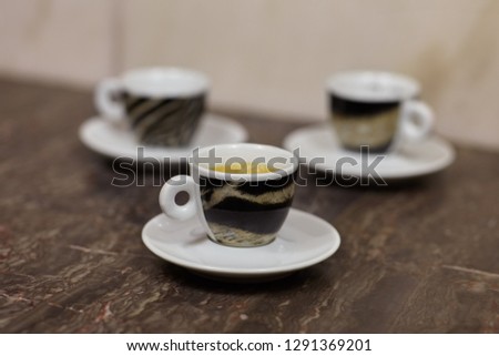 Close up picture of three little cups and saucers, with coffee espresso, with tiger pattern design, on marble background. Selective focus. Indoors, copy space.
