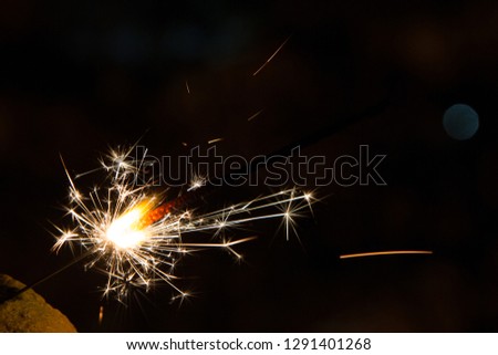 Bengal fire sparkles against the background of city lights, blurred bokeh.  A lot of sparks from the left