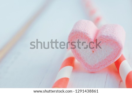 Sweet marshmallow in the shape of heart on wooden table. Decorated with pink straw. Concept about love and relationship with copy space. (Soft Style for Background) 
