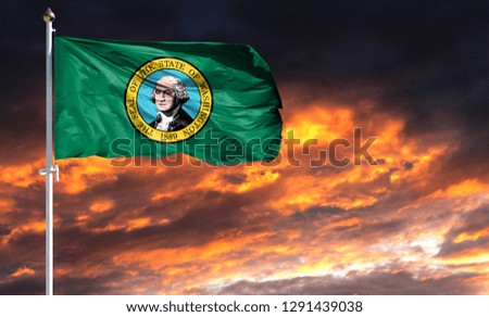 flag State of Washington on flagpole fluttering in the wind against a colorful sunset sky