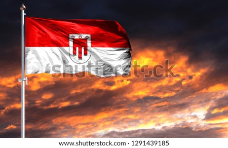 flag of Vorarlberg on flagpole fluttering in the wind against a colorful sunset sky