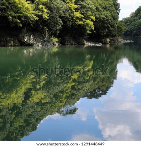 Amazingly beautiful and scenic landscape from Japan. In this photo you can see a forest growing on a mountain and it's colorful reflection on some perfectly calm water. Photographed during a sunny day