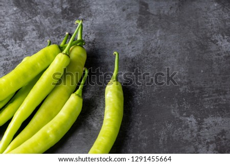 Fresh large green chilli on dark textured background, young pepper chilli with copy space