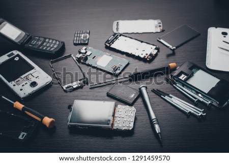 disassembled mobile phone and tools on wooden background