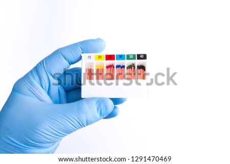Endodontic pins used to fill a tooth canal before putting fillings. Endodontic instruments. Hand holding a container with endodontic pins. Royalty-Free Stock Photo #1291470469