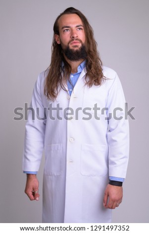 Portrait of young handsome bearded man doctor thinking