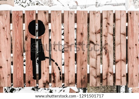 Symbol pissing boy on the wooden fence. Horizontal shot.