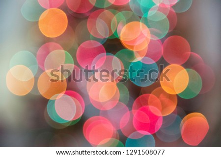 Glowing multi-colored light orbs created in-camera with lens from the bokeh effect to depict festive holiday mood.